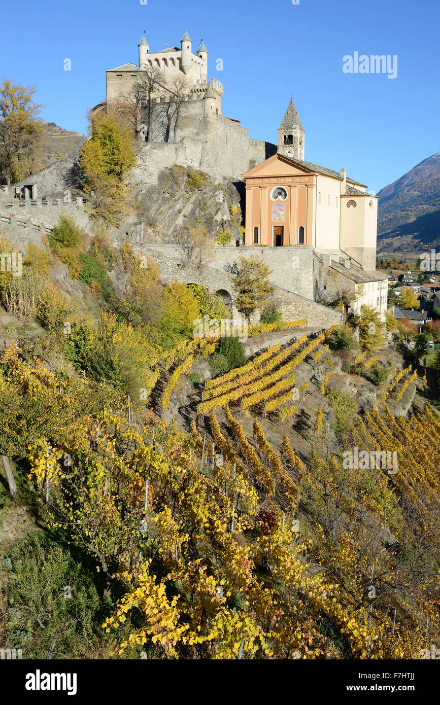 Schloss und Kirche Saint-Pierre über einem Weinberg mit herbstlichen Farben auf ihrem Höhepunkt. Aostatal, Italien. Stockfoto