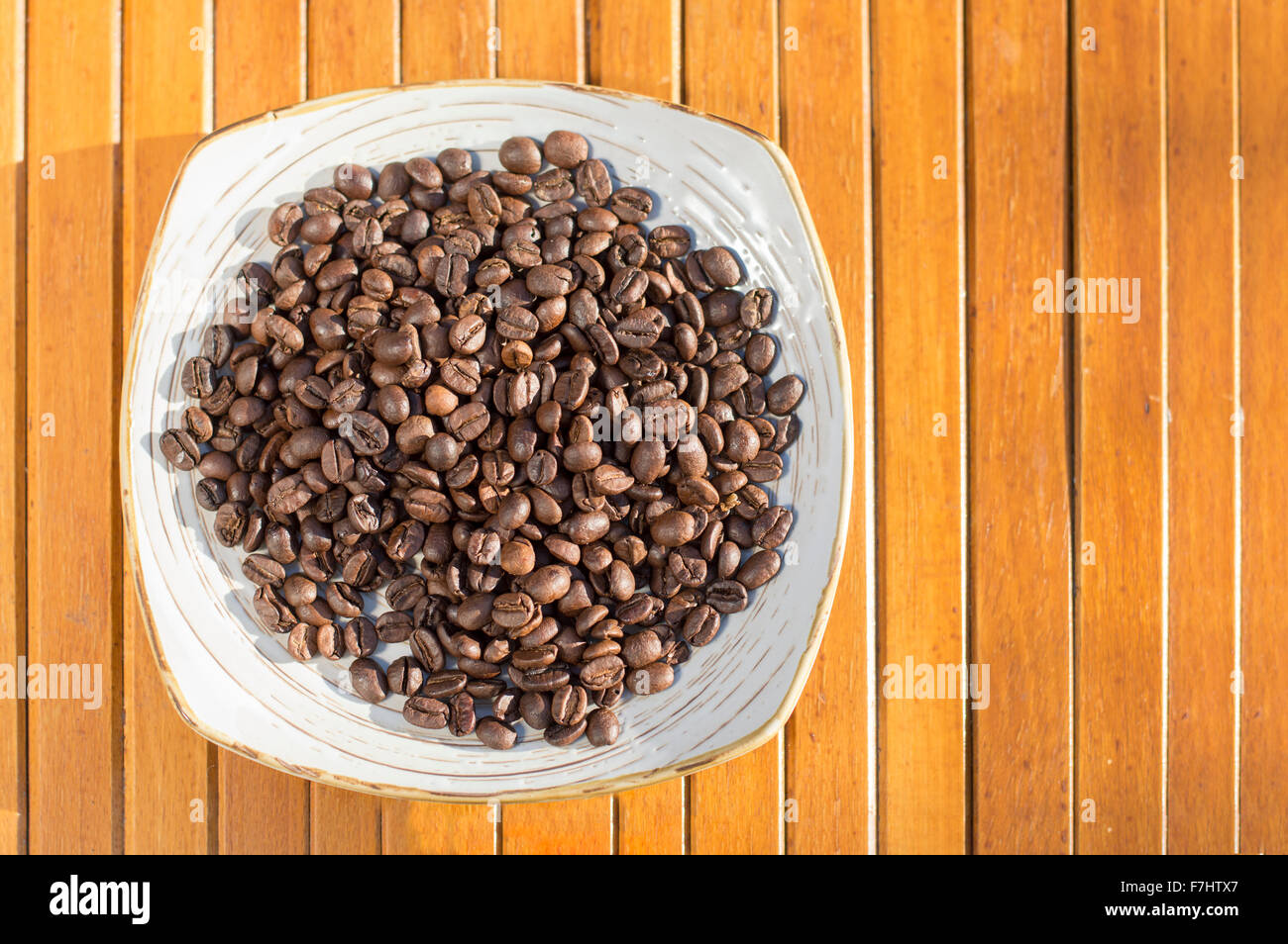 Kaffeebohnen in einem Teller platziert auf einem Holztisch Stockfoto