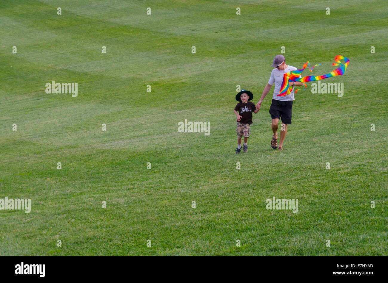 Ein Mann und sein Kind gehen mit einem Drachen auf Gras im National Arboretum Canberra, Australien Stockfoto
