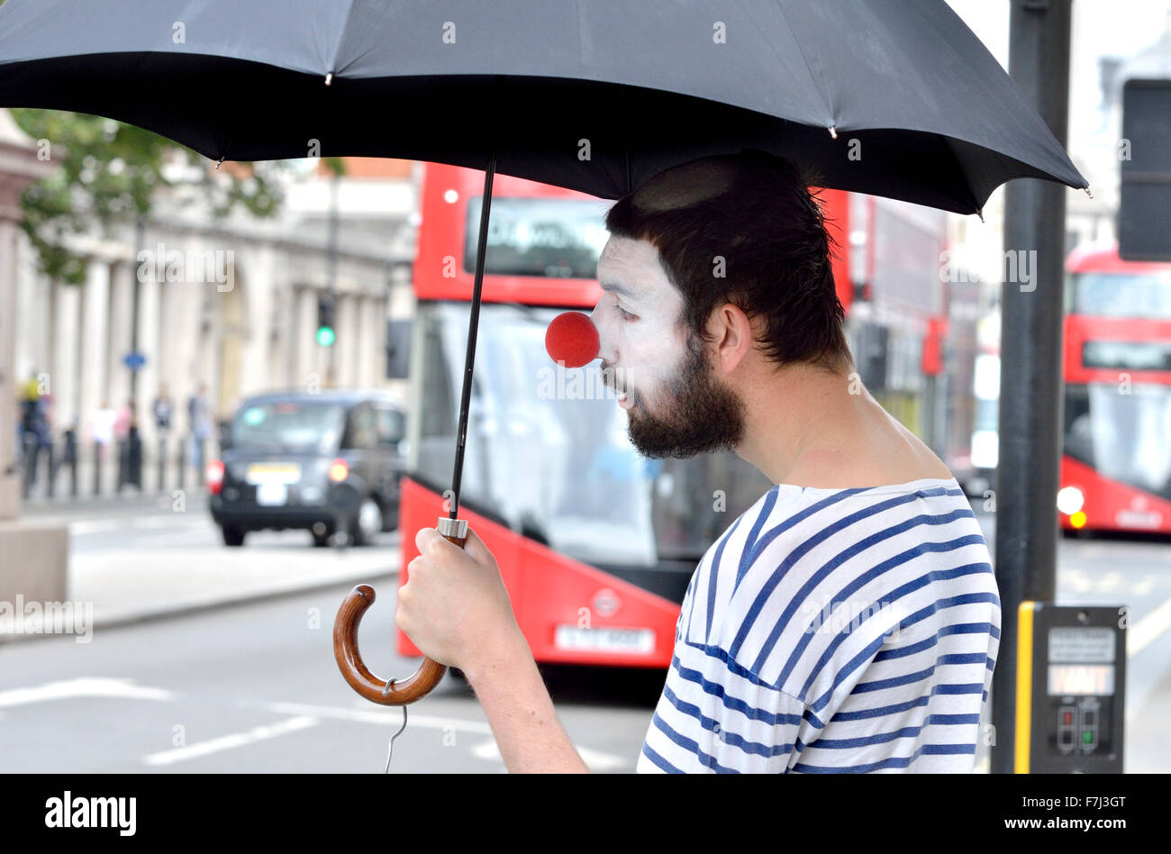 London, England, Vereinigtes Königreich. Clown mit einem Regenschirm in Parliament Square Stockfoto