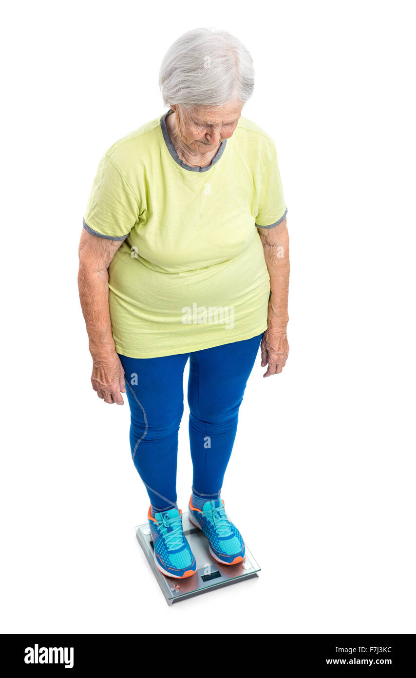 Ältere Frau wiegen sich auf Skalen auf weißem Hintergrund Stockfoto