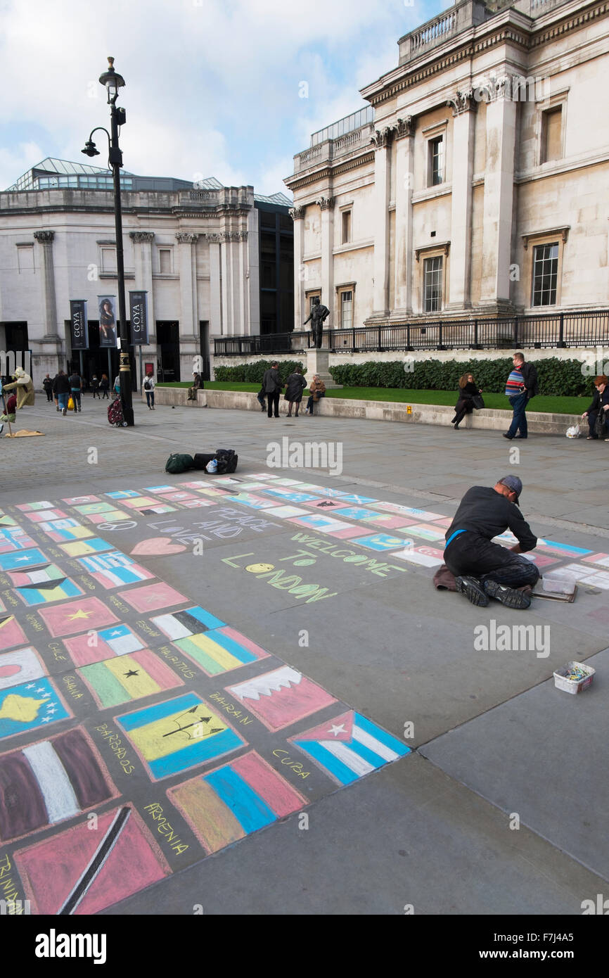 Street Performer Zeichnung die Flaggen der Welt mit Kreide auf dem Bürgersteig vor der National Gallery, London, Großbritannien Stockfoto