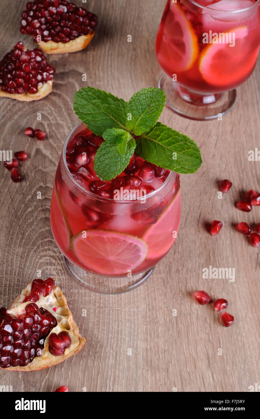 Granatapfel-cocktail mit Scheiben Limette, Minze und Eis Stockfoto