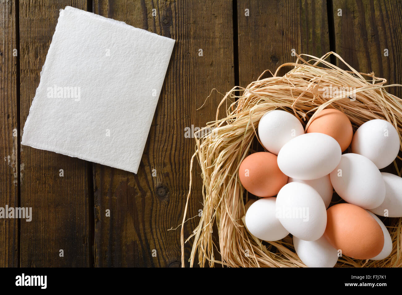 Eiern im strohig Nest mit Hand gemacht Papierkarte auf Vintage Holzbrett Stockfoto