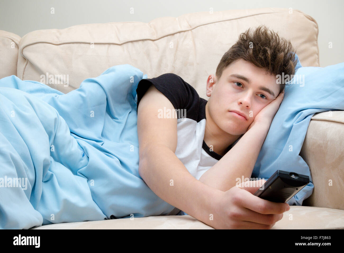 Teenager eingewickelt in eine Decke vor dem Fernseher Stockfoto