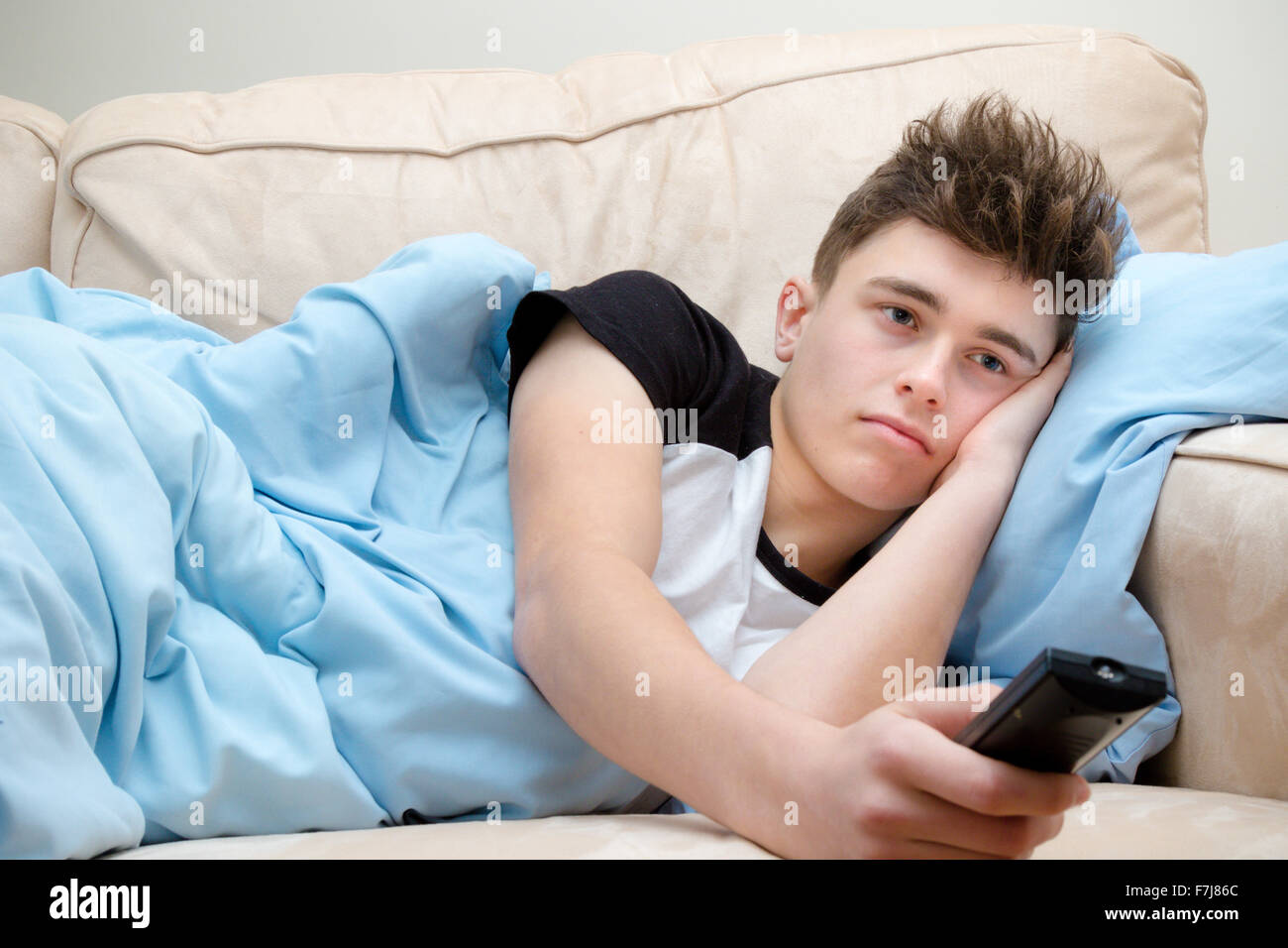 Teenager eingewickelt in eine Decke vor dem Fernseher Stockfoto