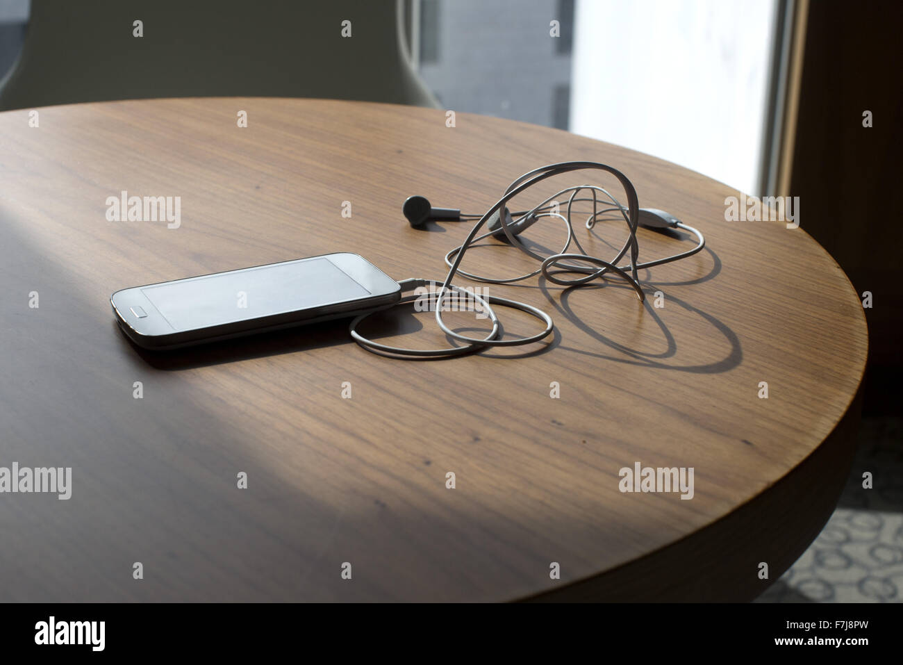 Smartphone und Ohrhörer auf Tisch Stockfoto