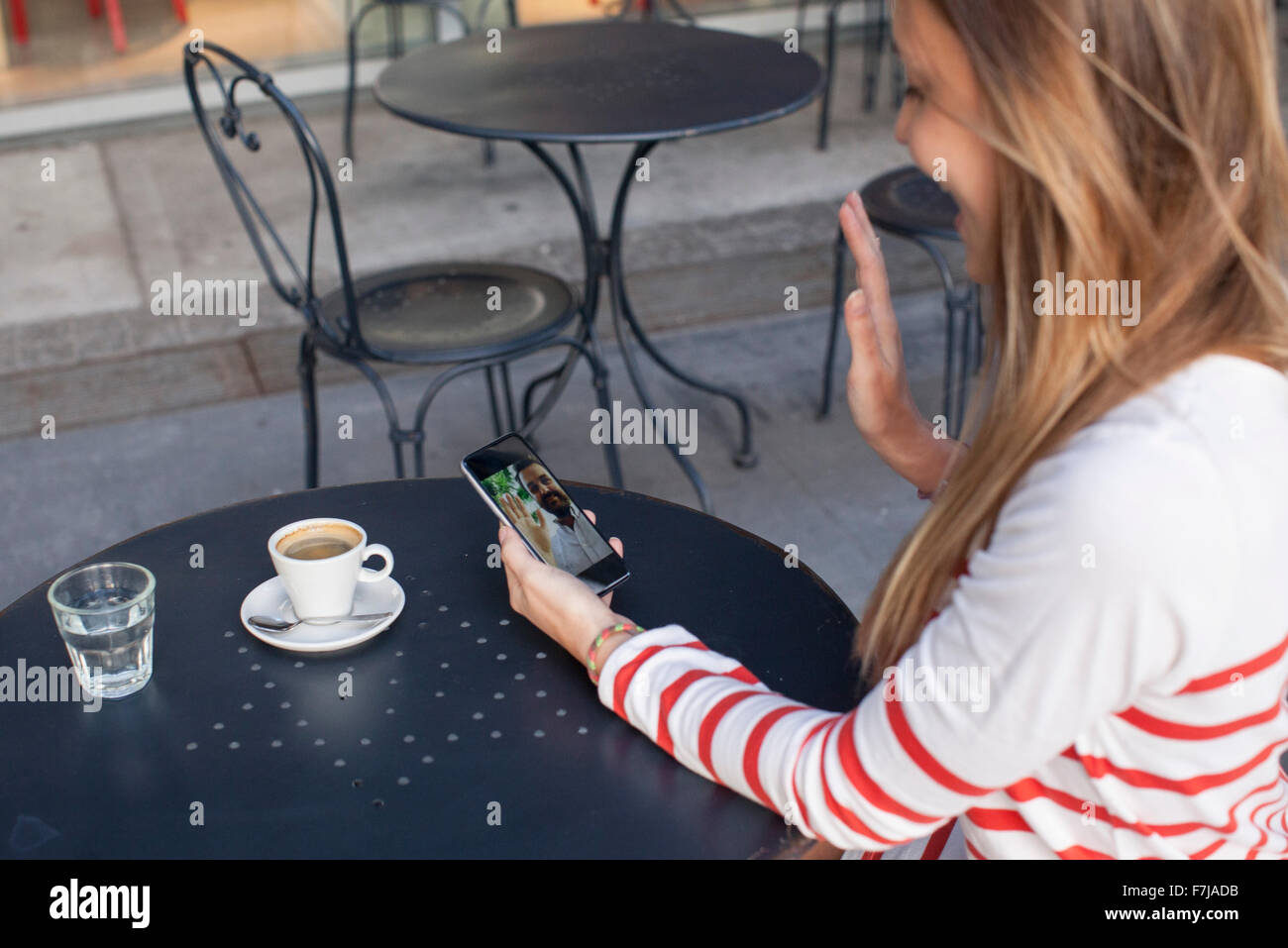Junge Frau mit Smartphone zum Videochat im café Stockfoto