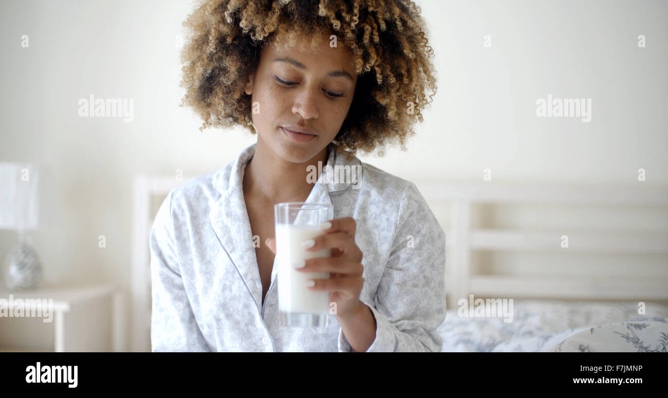 Frau trinkt eine Milch auf Bett Stockfoto