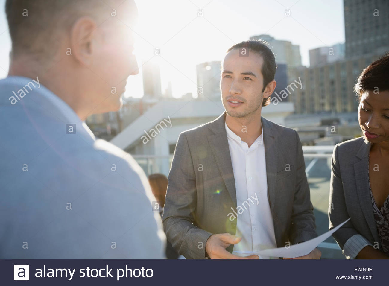 Business-Leute diskutieren Papierkram auf sonnigen städtischen Dach Stockfoto