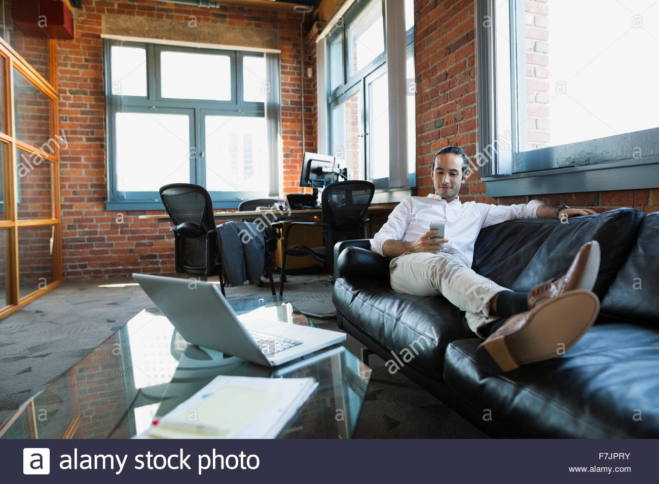 Komfortable Geschäftsmann SMS auf Büro-sofa Stockfoto
