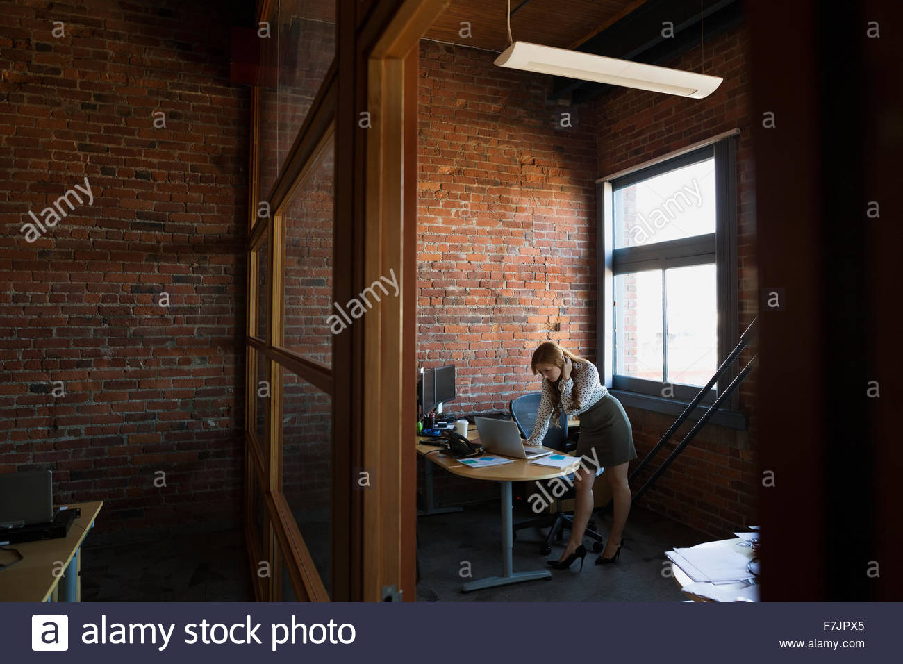 Geschäftsfrau, beugte sich über Laptop im Büro Stockfoto