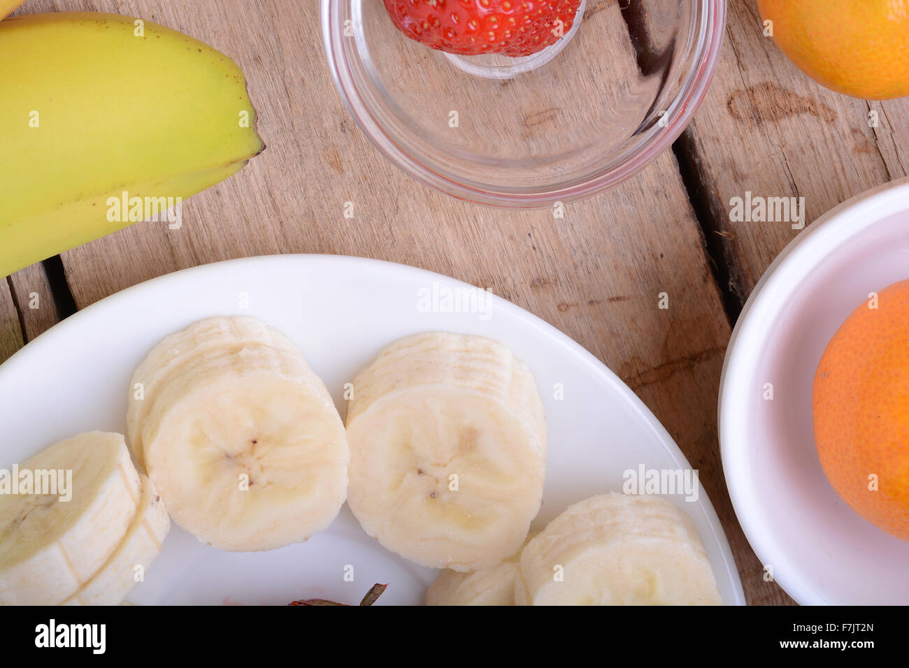 gesunde Erdbeeren und Bananen Scheiben auf hölzernen Hintergrund Stockfoto