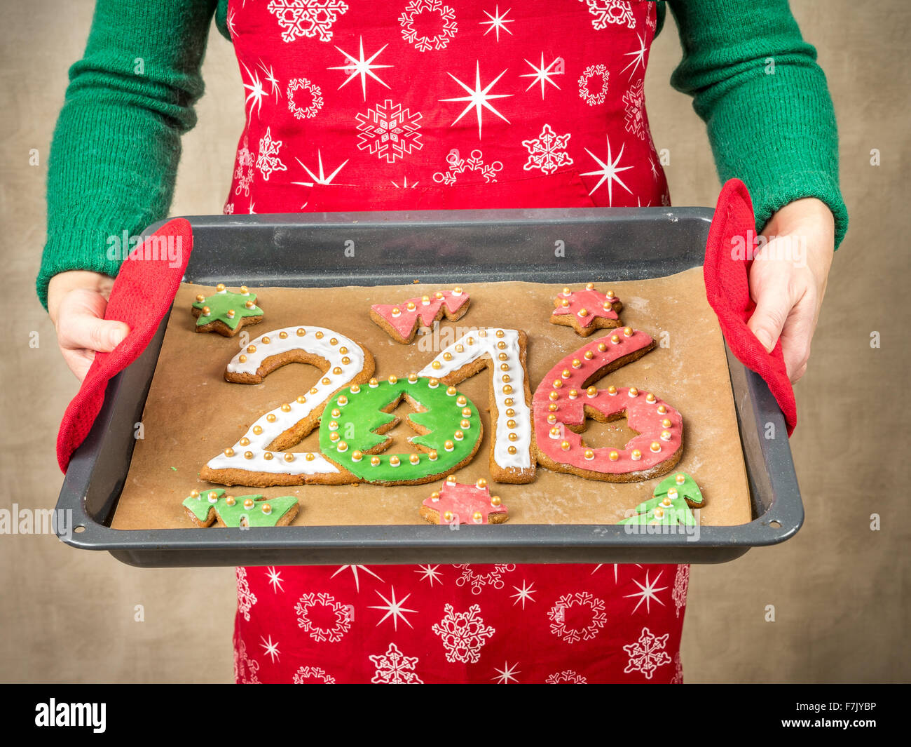 Frau trägt rote Schürze halten hausgemachte Lebkuchen in Form von 2016 neu Jahr Ziffern auf Backblech Stockfoto