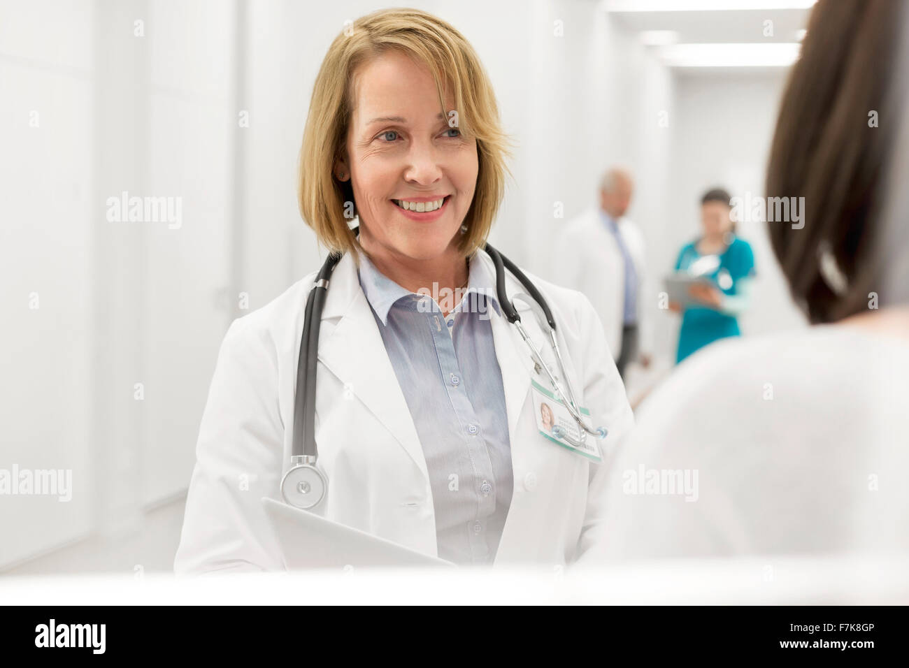 Arzt im Gespräch mit Patienten im Krankenhausflur lächelnd Stockfoto