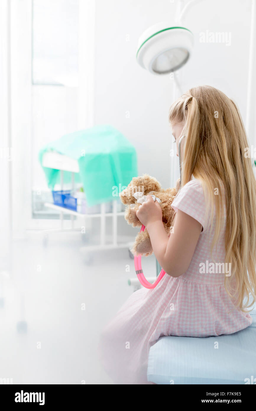 Mädchen mit Stethoskop auf Teddybär im Untersuchungsraum Stockfoto