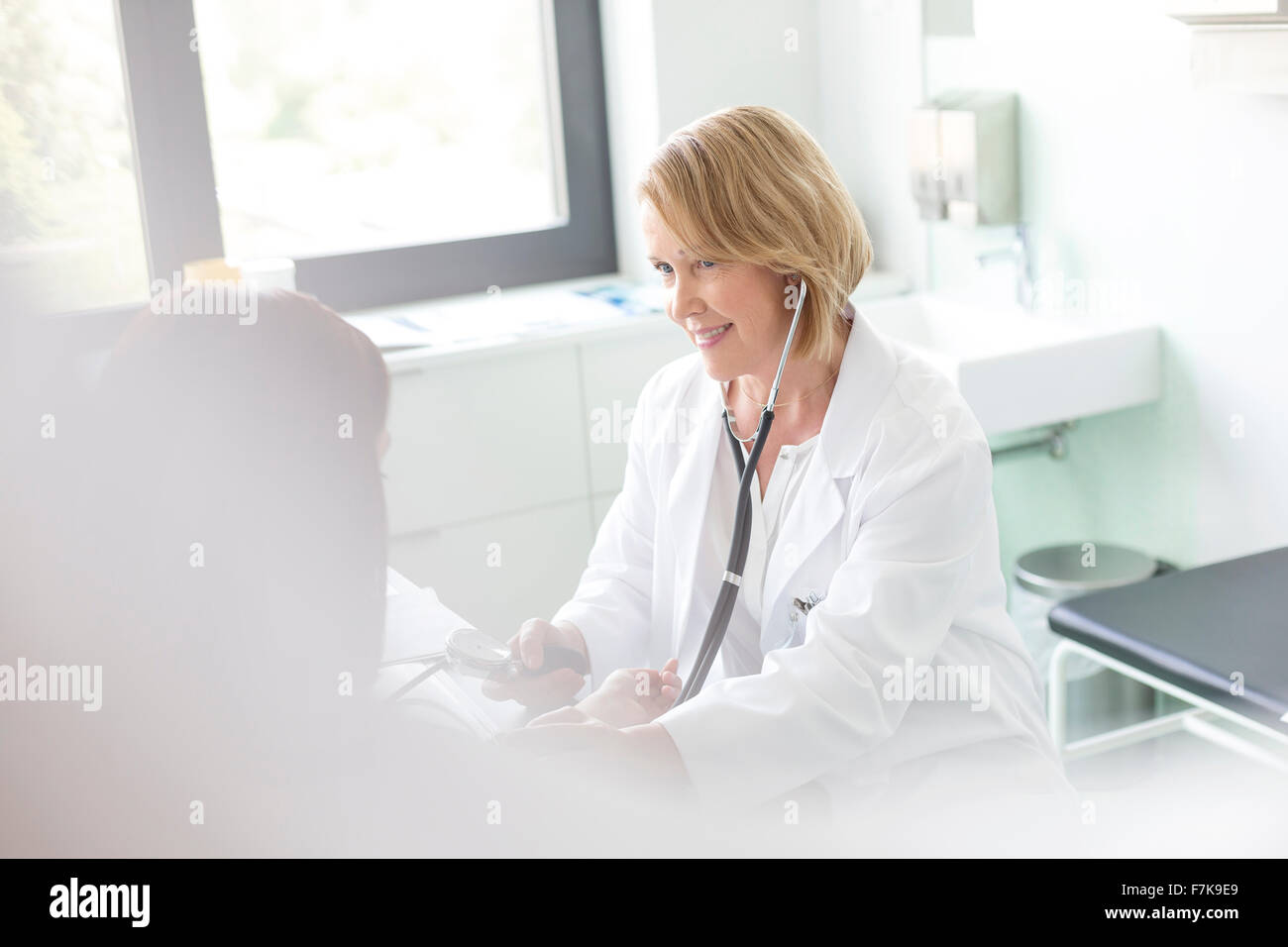 Arzt überprüft Patient Blutdruck im Untersuchungsraum Stockfoto