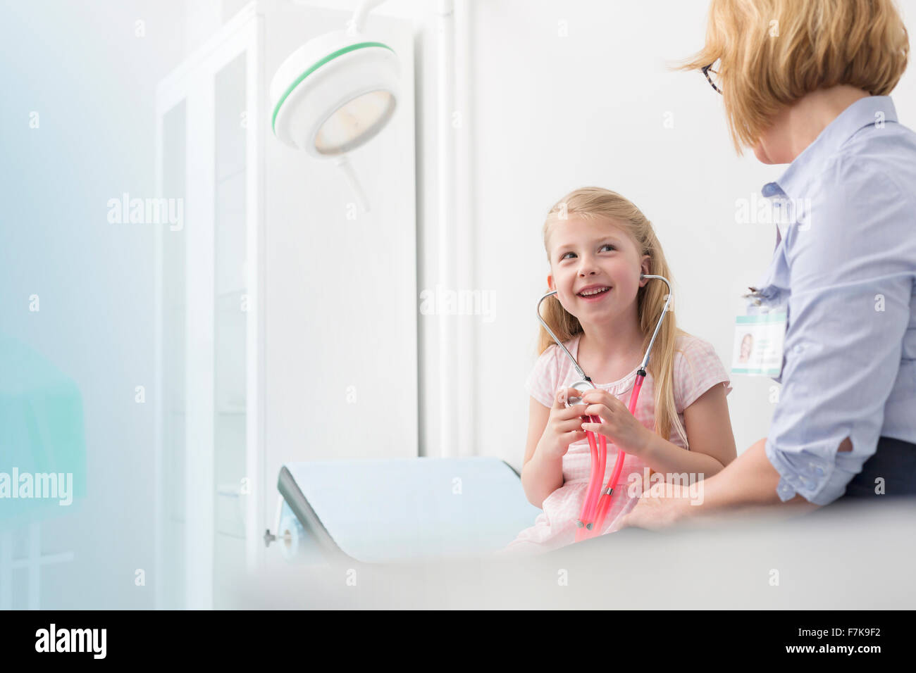 Kinderarzt beobachten Mädchen Patienten spielen mit Stethoskop im Untersuchungsraum Stockfoto