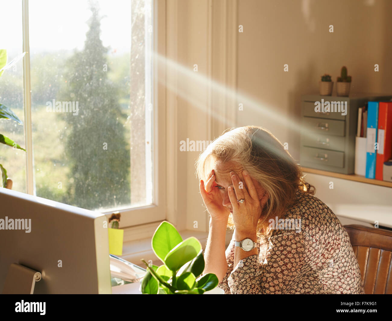 Betonte Frau über Computer in sonnigen home-office Stockfoto