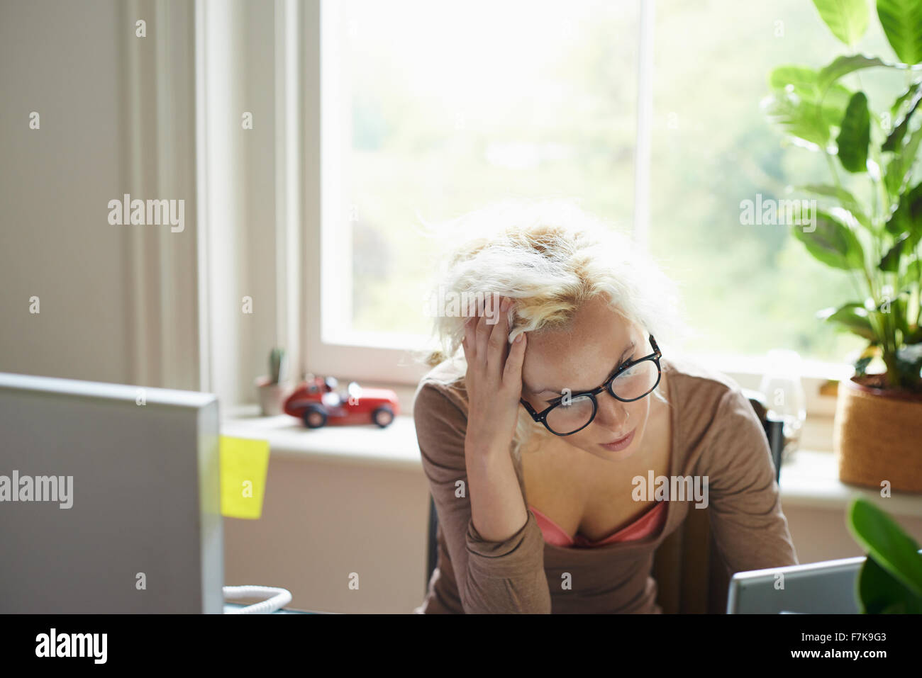 Betonte Frau mit Händen im Haar, die im Büro arbeiten Stockfoto