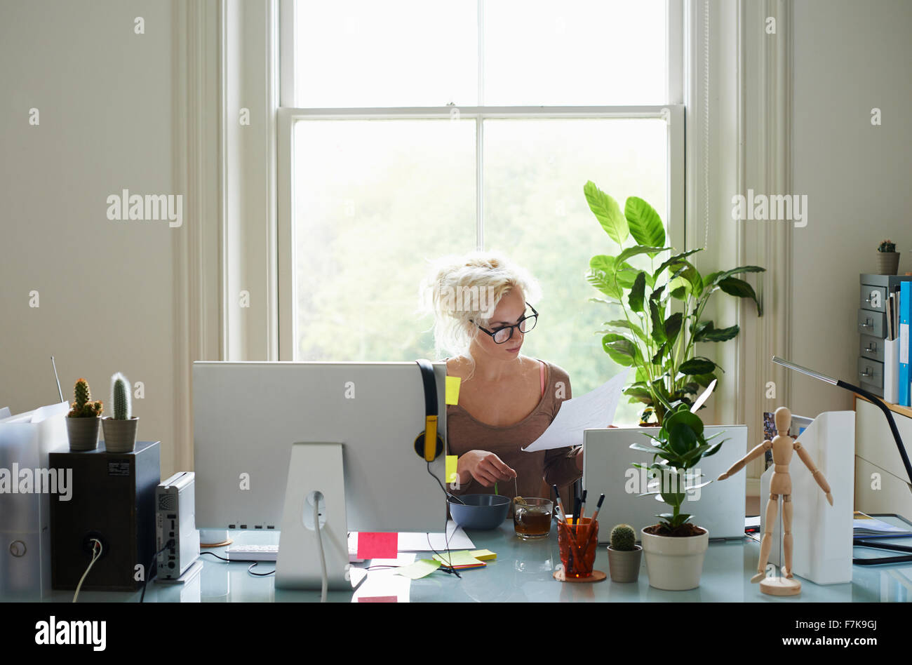 Junge Frau liest Papierkram am Schreibtisch im home-office Stockfoto