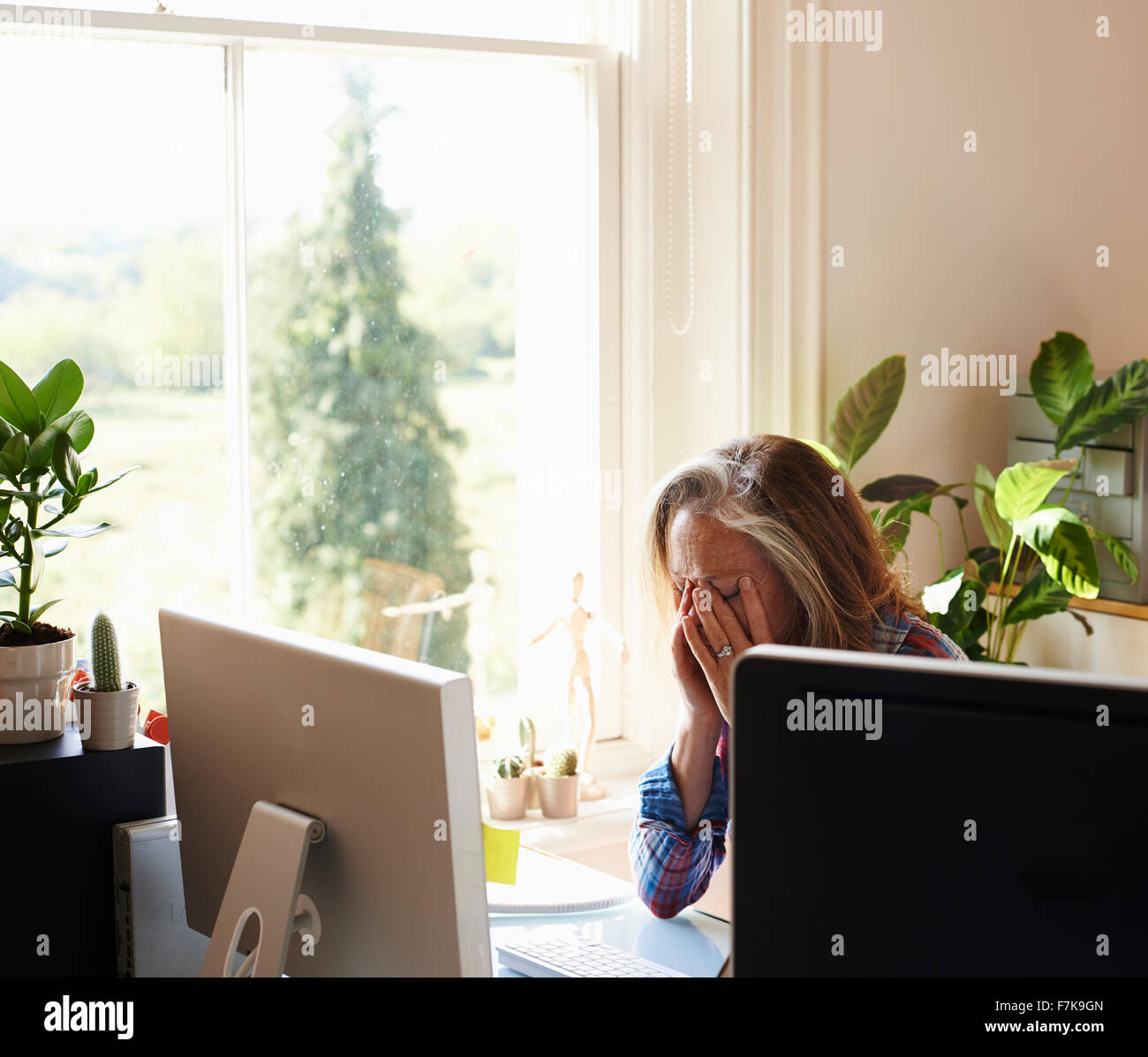Müde Frau mit Kopf in Händen am Computer im Büro zu Hause Stockfoto