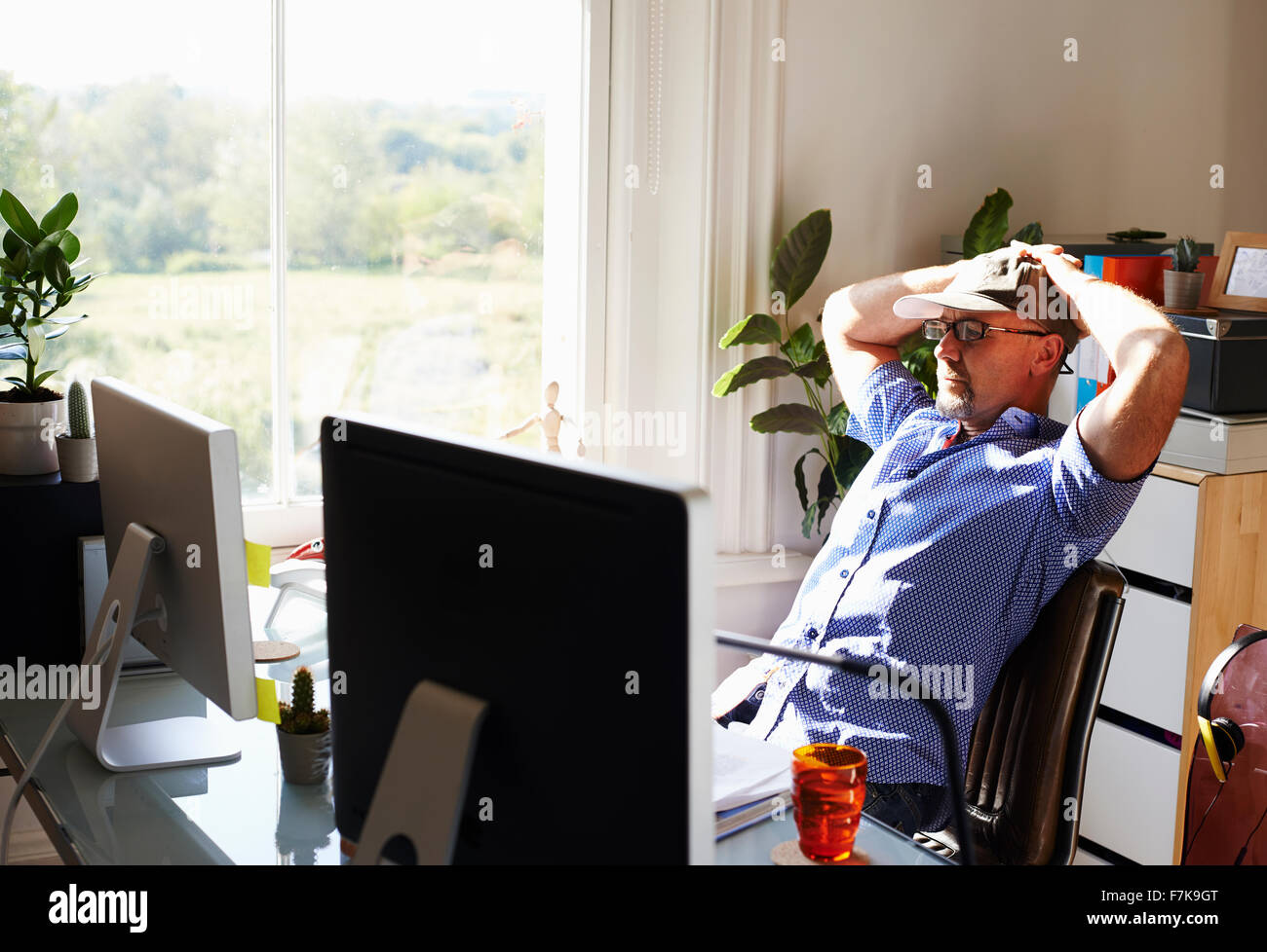 Man lehnt sich zurück arbeiten am Computer in sonnigen Heimbüro Stockfoto