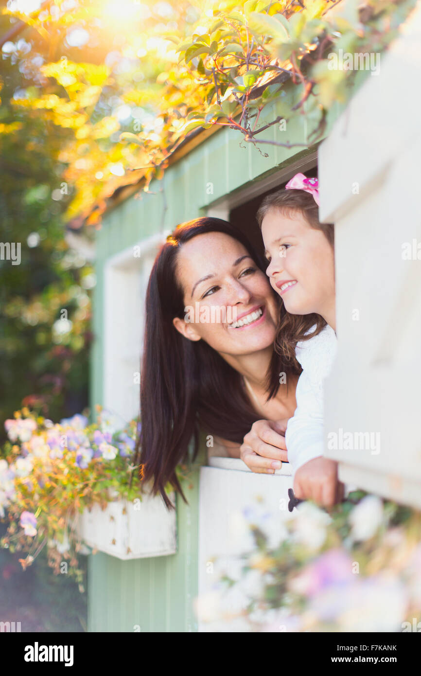 Lächelnde Mutter und Tochter im Spielhaus-Fenster Stockfoto