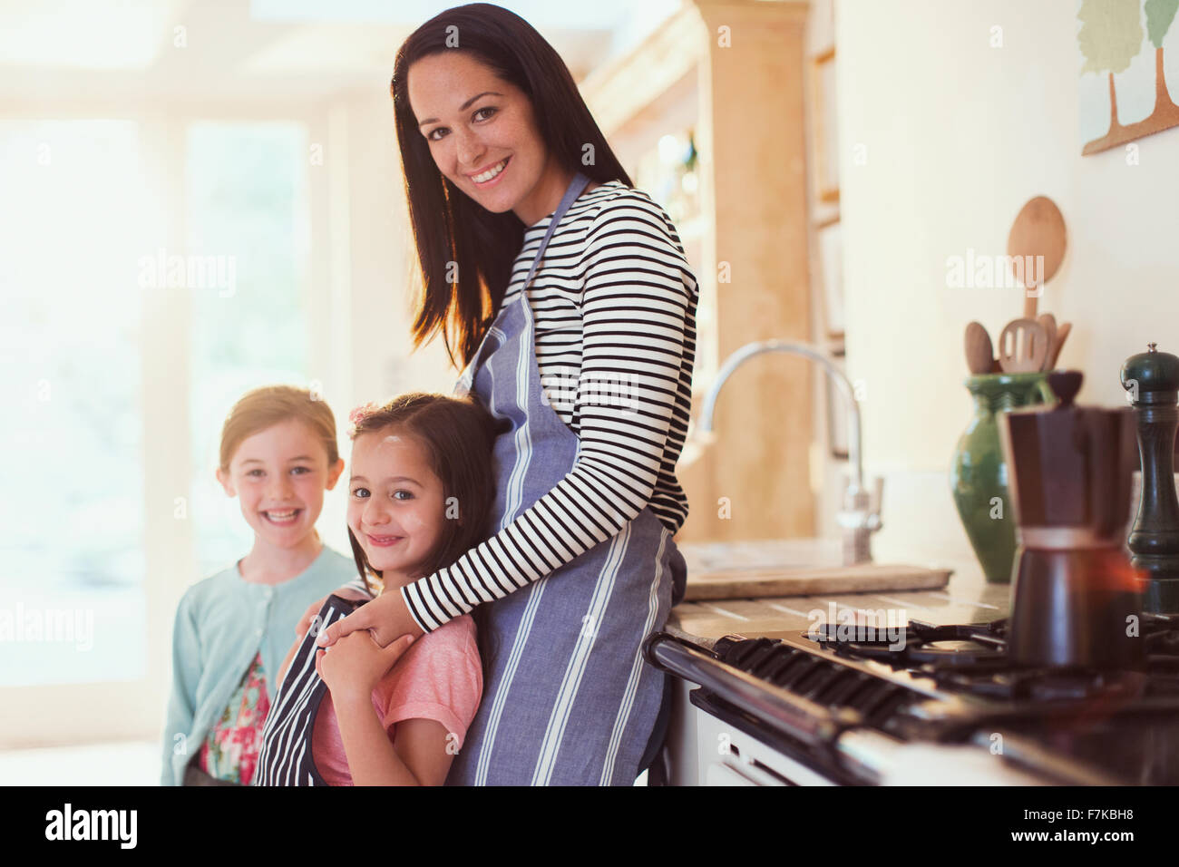 Porträt, Lächeln, Mutter und Töchter in Küche Stockfoto