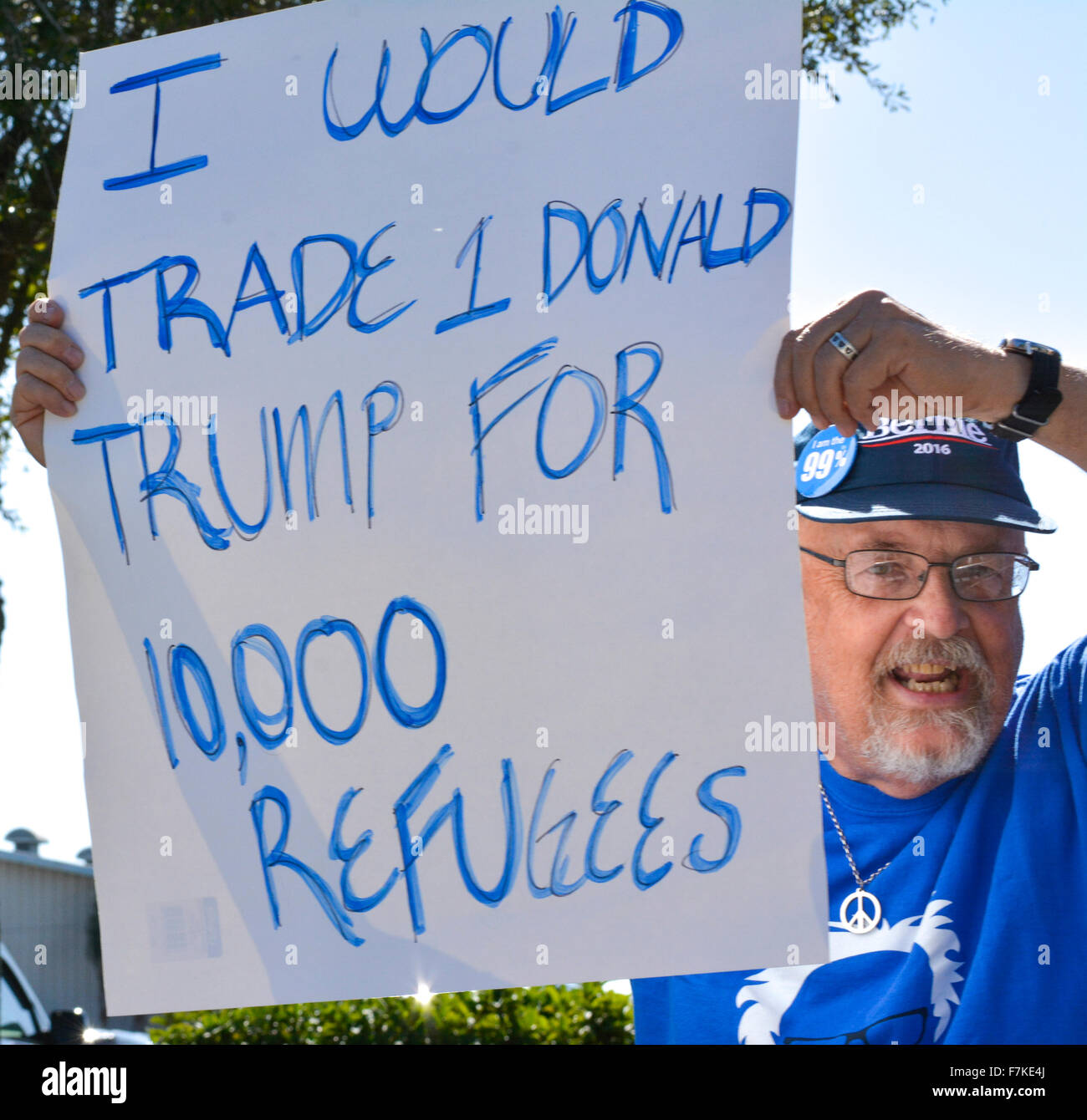 Ein Mann mit Bernie Sanders Hut hält ein Protest-Zeichen in Bezug auf Donald Trump Position über die syrische Flüchtlinge in einer GOP-Rallye Stockfoto