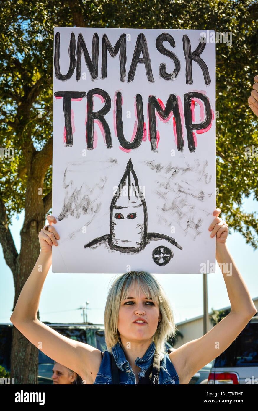Eine attraktive junge Frau Demonstrant hält eine Handarbeit mit KKK Charakter entlarven Trump bei Donald Trump politische Kundgebung Schild Stockfoto