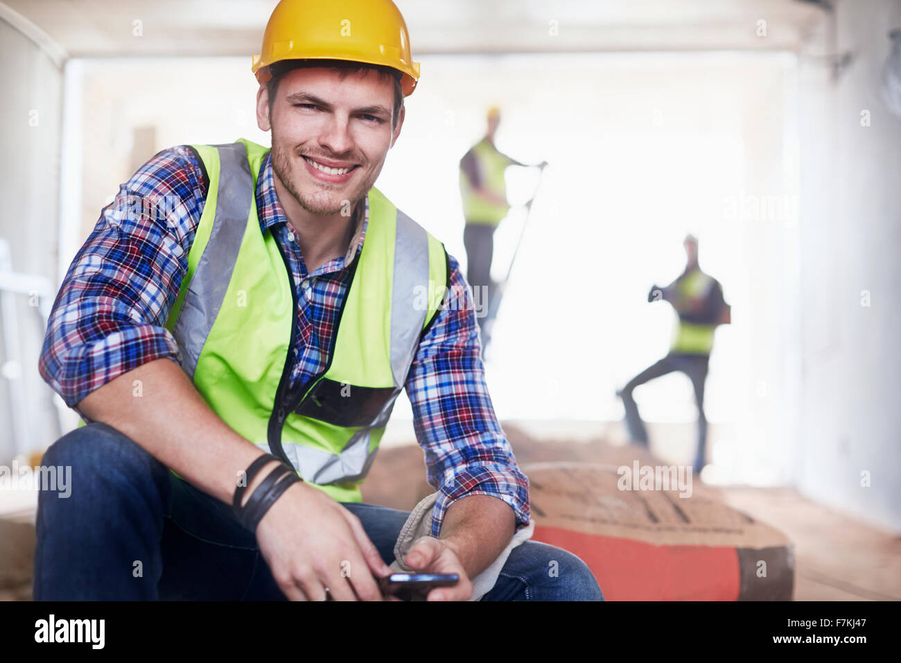 Porträt lächelnd Bauarbeiter mit Handy auf Baustelle Stockfoto
