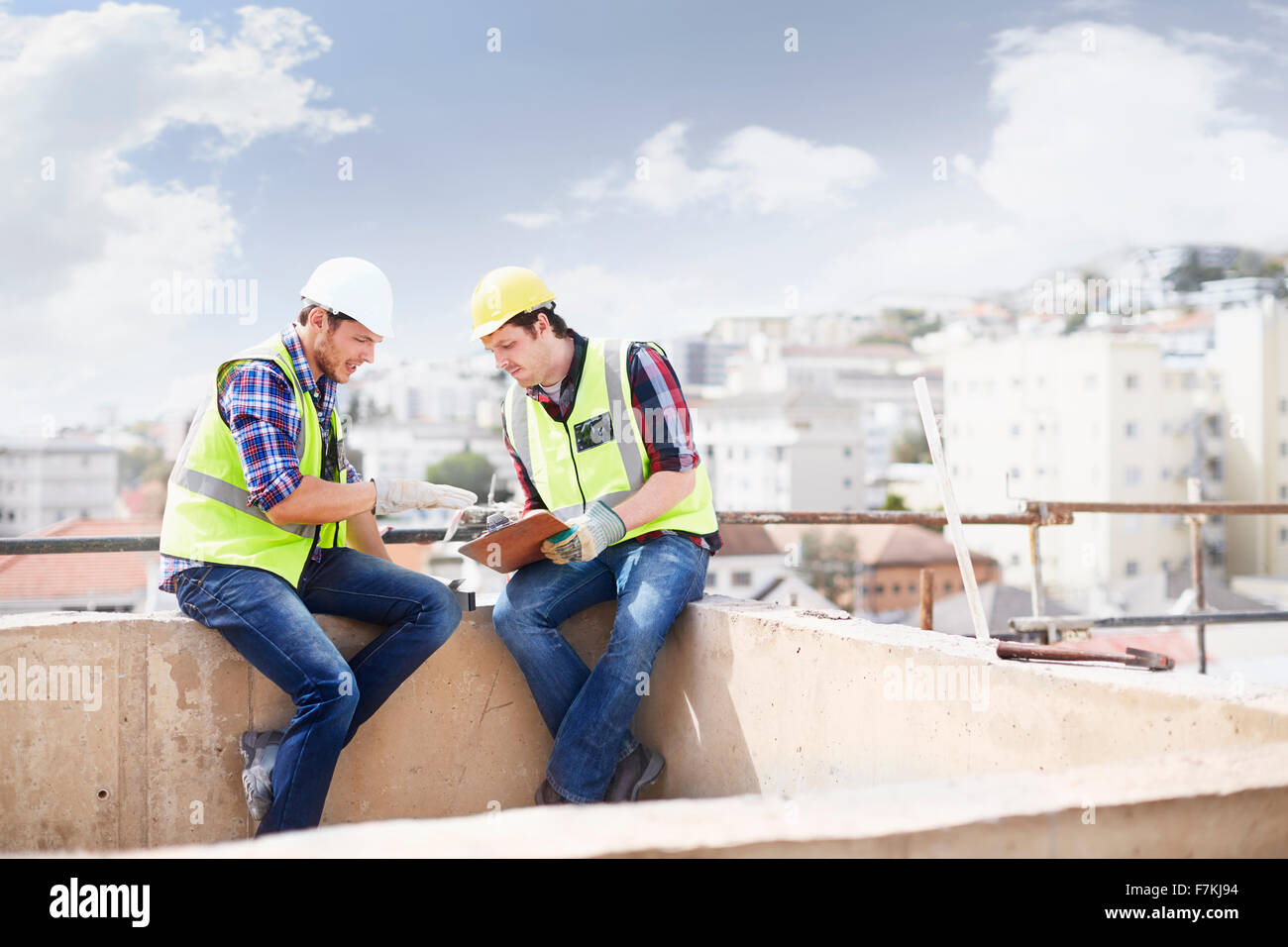 Bauarbeiter und Ingenieur mit Zwischenablage auf Hochhaus-Baustelle im Gespräch Stockfoto