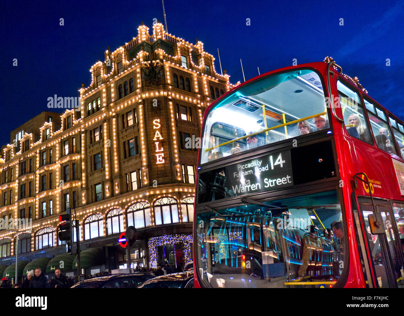Das Kaufhaus Harrods in der Abenddämmerung mit Verkauf leuchtet Shopper vorbei an Taxis und roten Bus Knightsbridge London SW1 Stockfoto