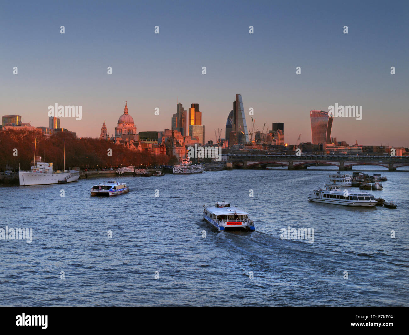 Panoramablick Stadtbild auf Stadt von London Saint Paul & Themse von Waterloo Bridge bei Sonnenuntergang mit zwei RB Thames Clipper Schiffe London UK Stockfoto