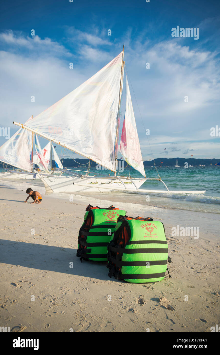 BORACAY, Philippinen - 20. Mai 2015: Grüne Schwimmwesten an einem tropischen Strand mit einigen Segelbooten im Hintergrund Stockfoto
