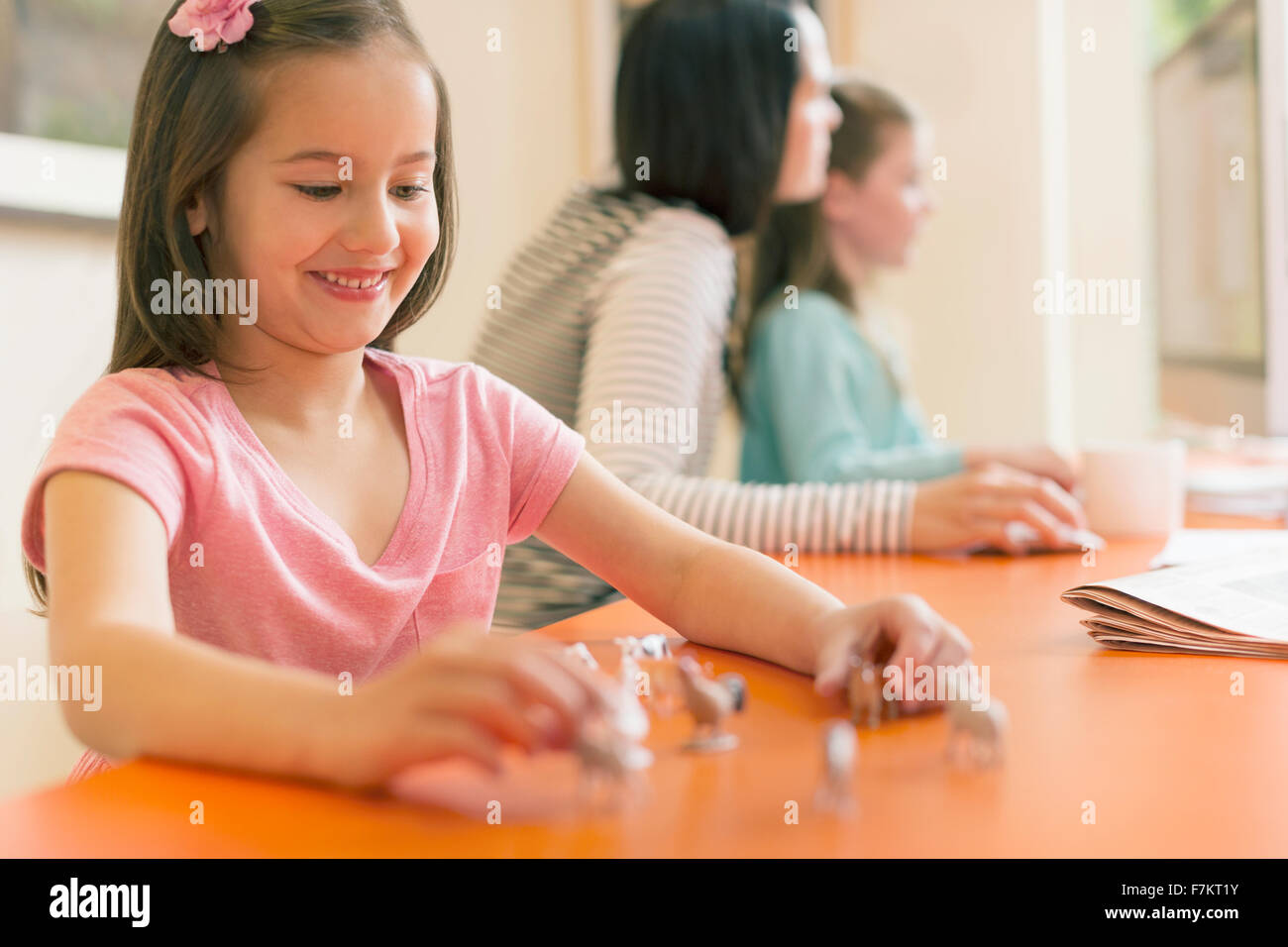 Lächelndes Mädchen spielen mit Miniatur-Spielzeug-Tiere Stockfoto
