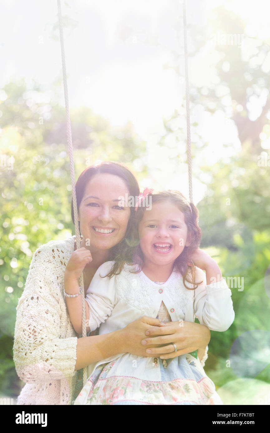 Porträt lächelnde Mutter umarmt Tochter auf Schaukel im park Stockfoto