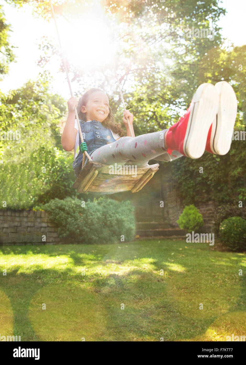 Begeisterte Mädchen schwingen im sonnigen Hinterhof Stockfoto