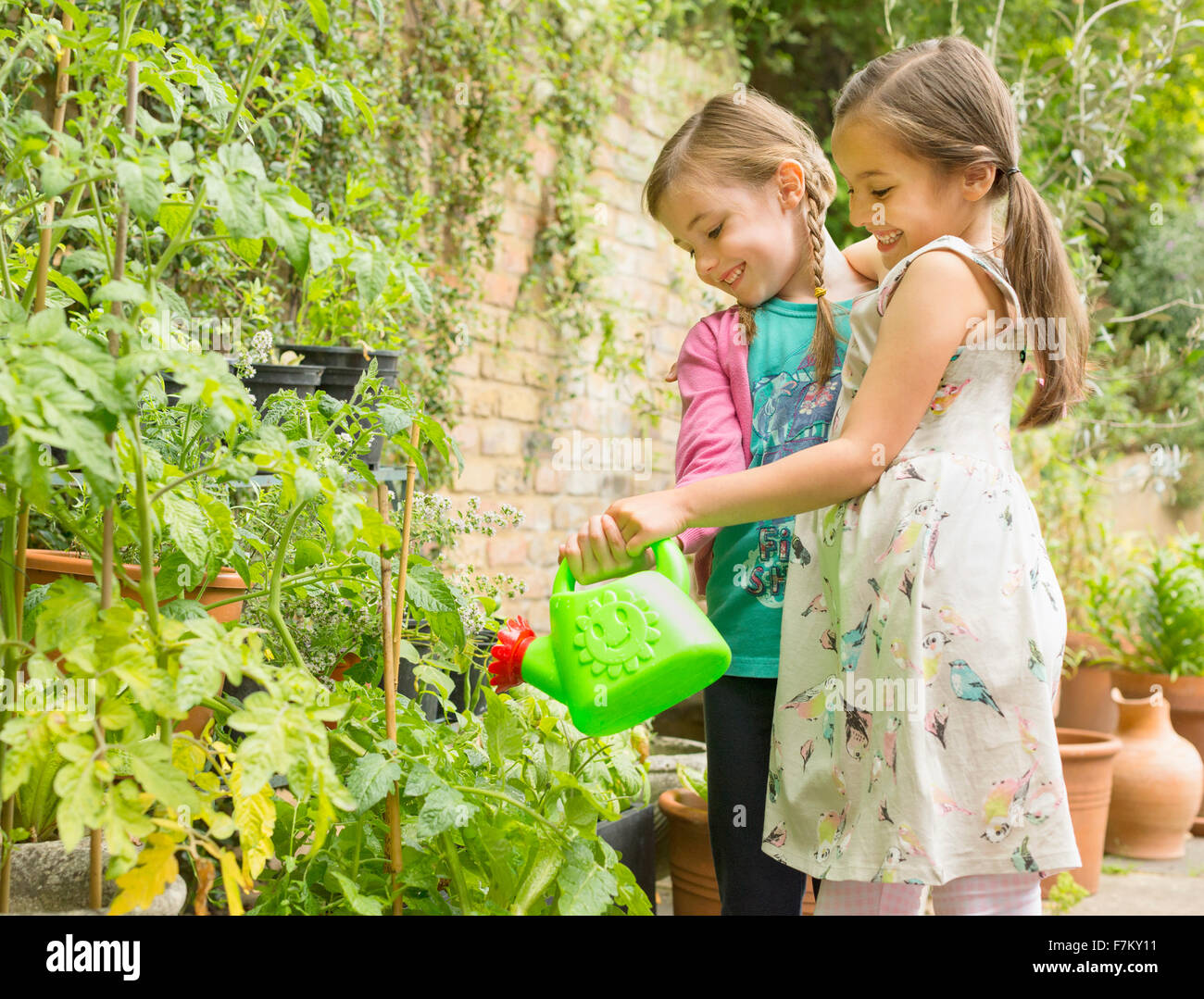 Umarmt Mädchen Bewässerung von Pflanzen im Garten Stockfoto