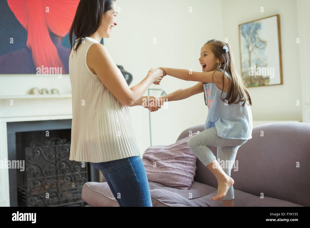 Spielerische Mutter und Tochter im Wohnzimmer tanzen Stockfoto