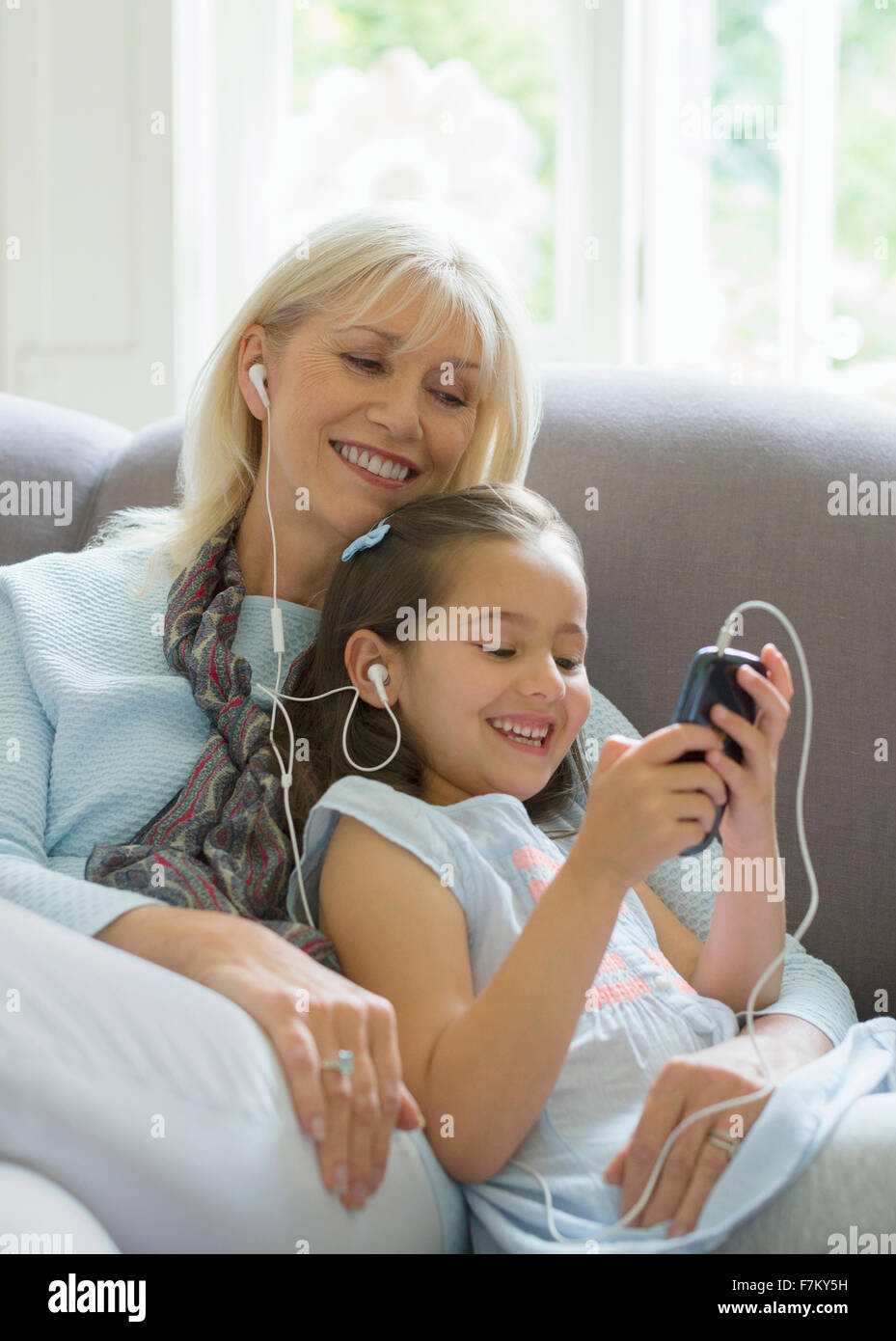 Großmutter und Enkelin teilen Kopfhörer anhören von Musik auf sofa Stockfoto