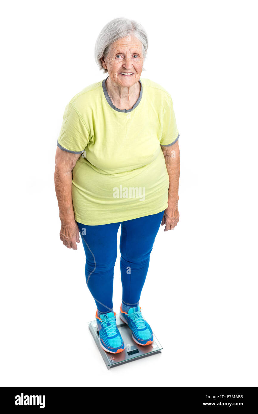 Ältere Frau wiegen sich auf Skalen auf weißem Hintergrund Stockfoto