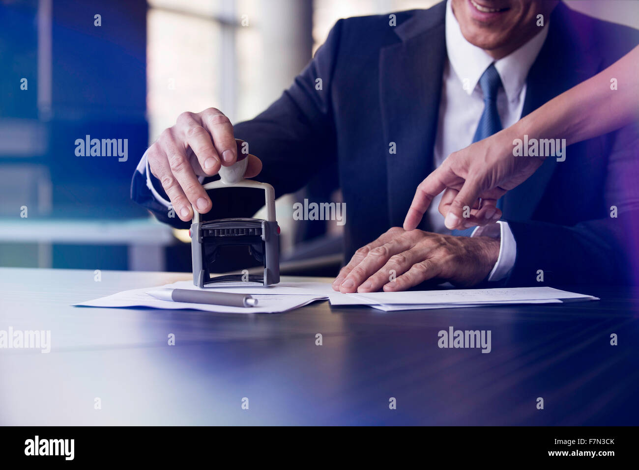 Geschäftsmann Stempeln Dokument mit Hilfe des Assistenten Stockfoto