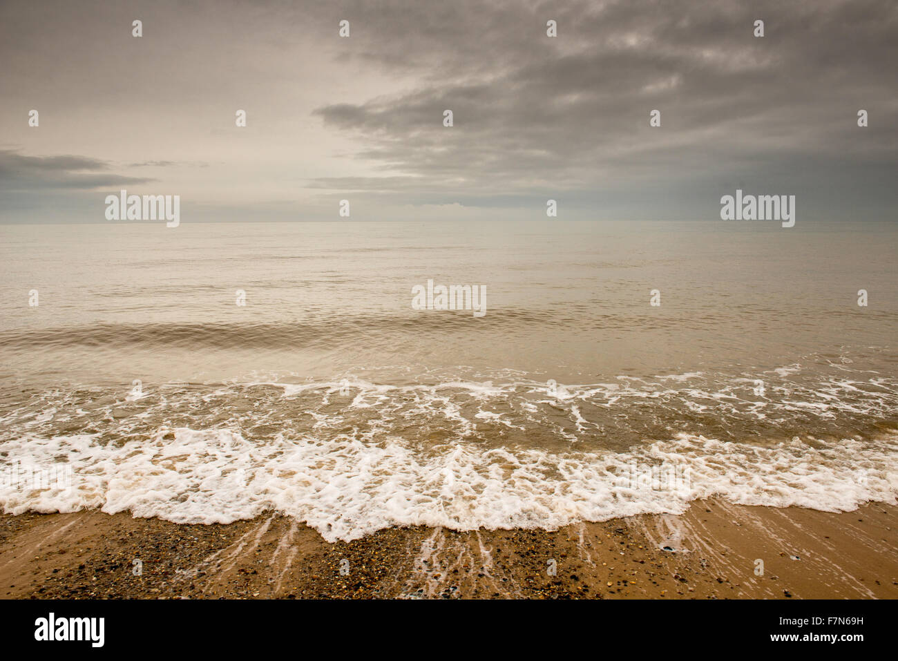 Welle zu einem steinigen Strand und Himmel einschalten Stockfoto