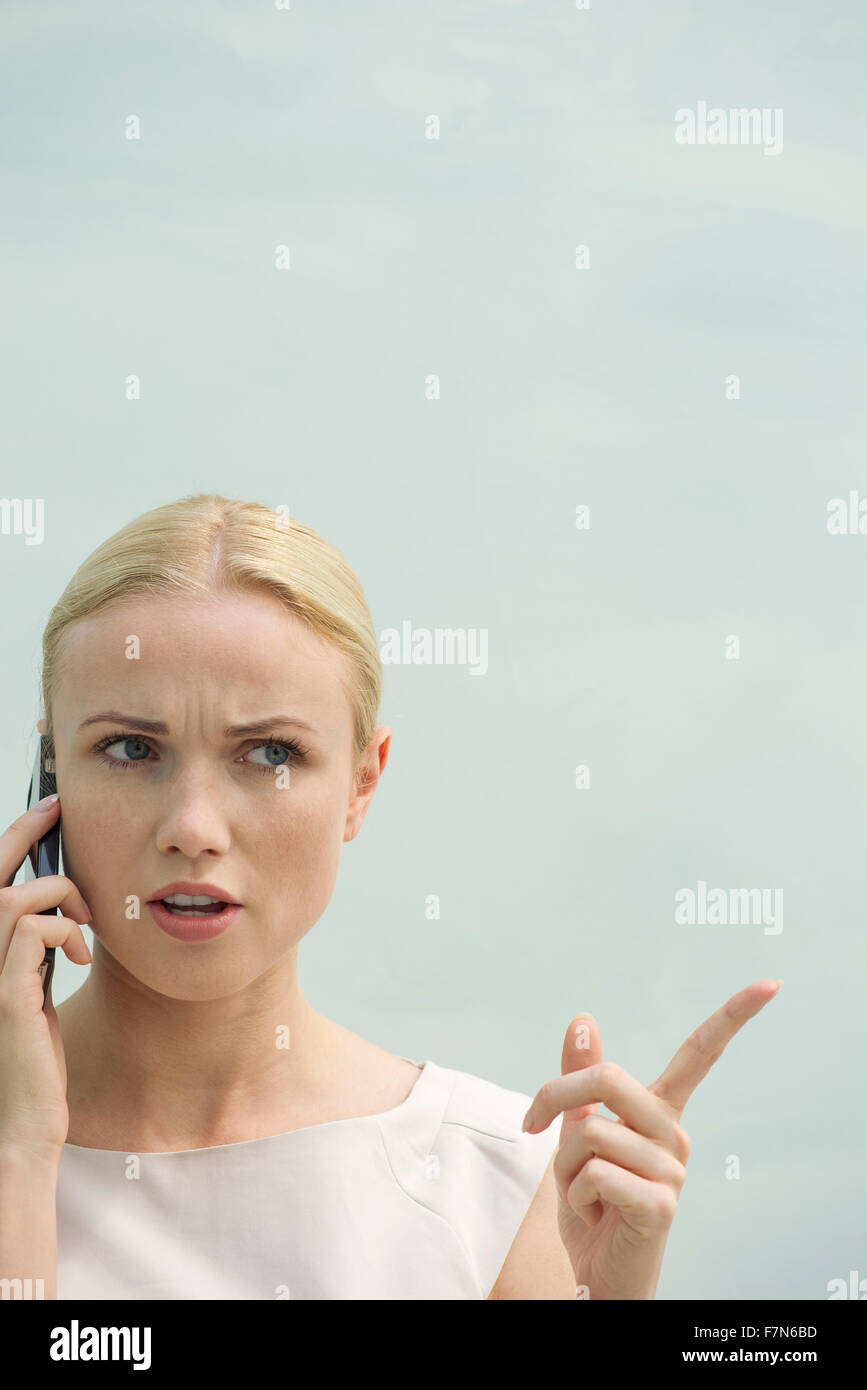 Frau macht wütendes Gesicht während des Gesprächs auf Handy Stockfoto