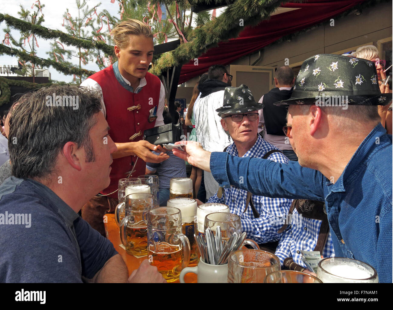 Bezahlung für Bier, Tisch mit Männern beim Oktoberfest, München, Bayern, Deutschland Stockfoto