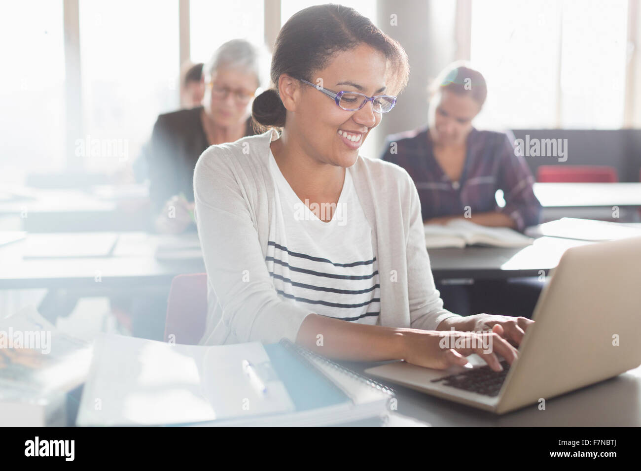 Lächelnde Frau, die Sie am Laptop in Erwachsenenbildung Klasse eingeben Stockfoto