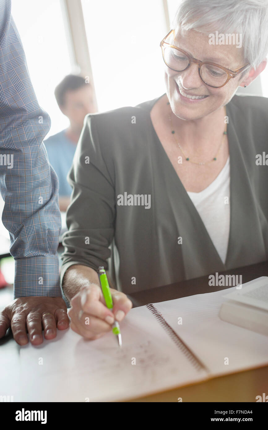 Ältere Frau, die Überprüfung der Hausaufgaben in Erwachsenenbildung Klassenzimmer Stockfoto