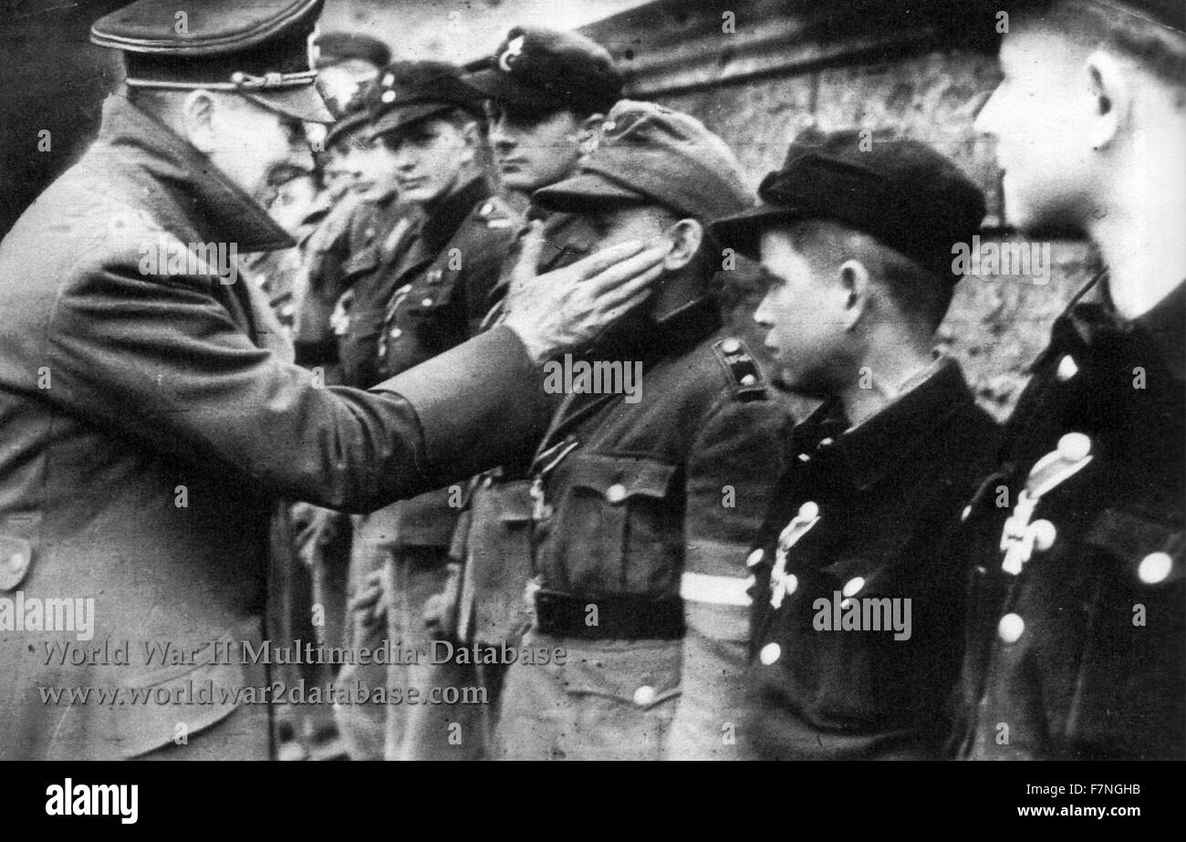Adolf Hitler berührt das Gesicht von Wilhelm Willi Hubner (1929-April 12, 2010) der jüngste Empfänger des Eisernen Kreuzes. Datiert 1945 Stockfoto